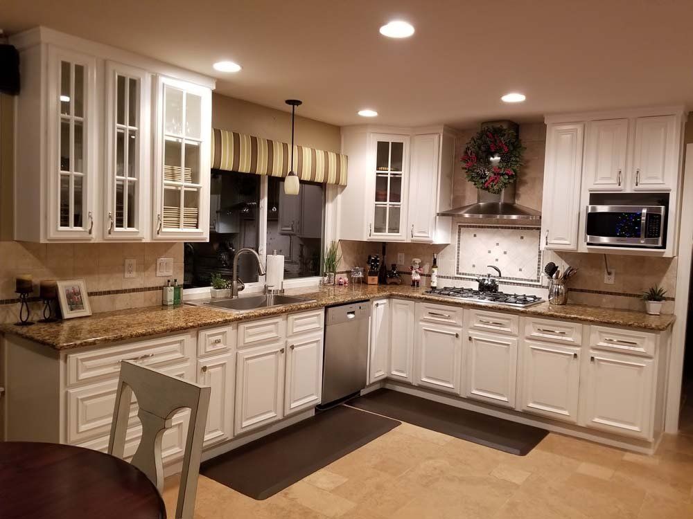 A kitchen with white cabinets and granite counter tops.