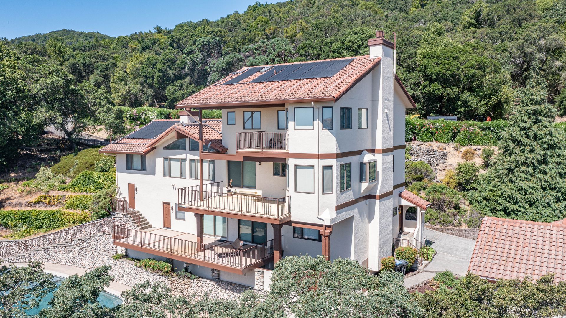 An aerial view of a large white house on top of a hill surrounded by trees.
