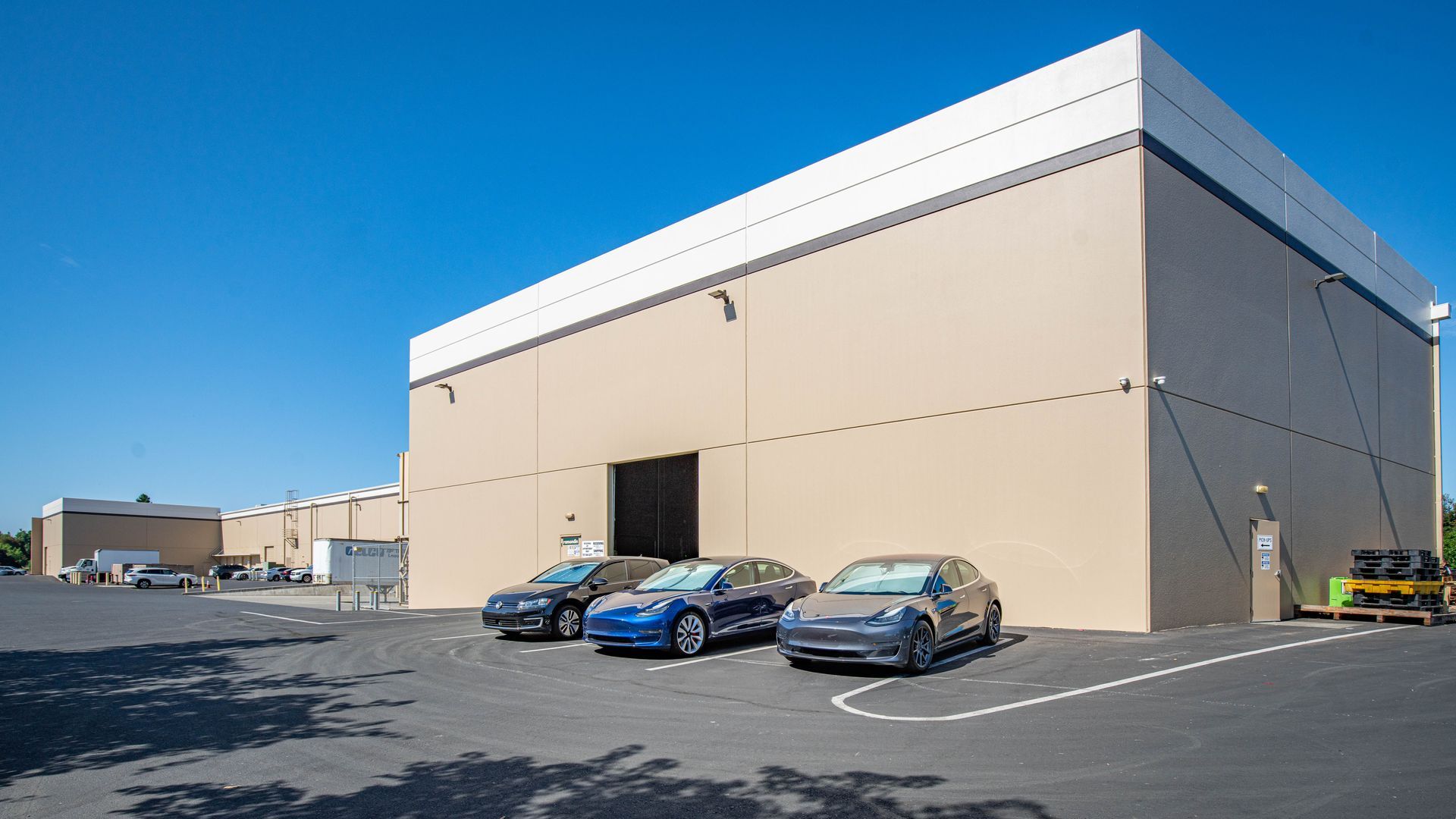 Three cars are parked in front of a large building.
