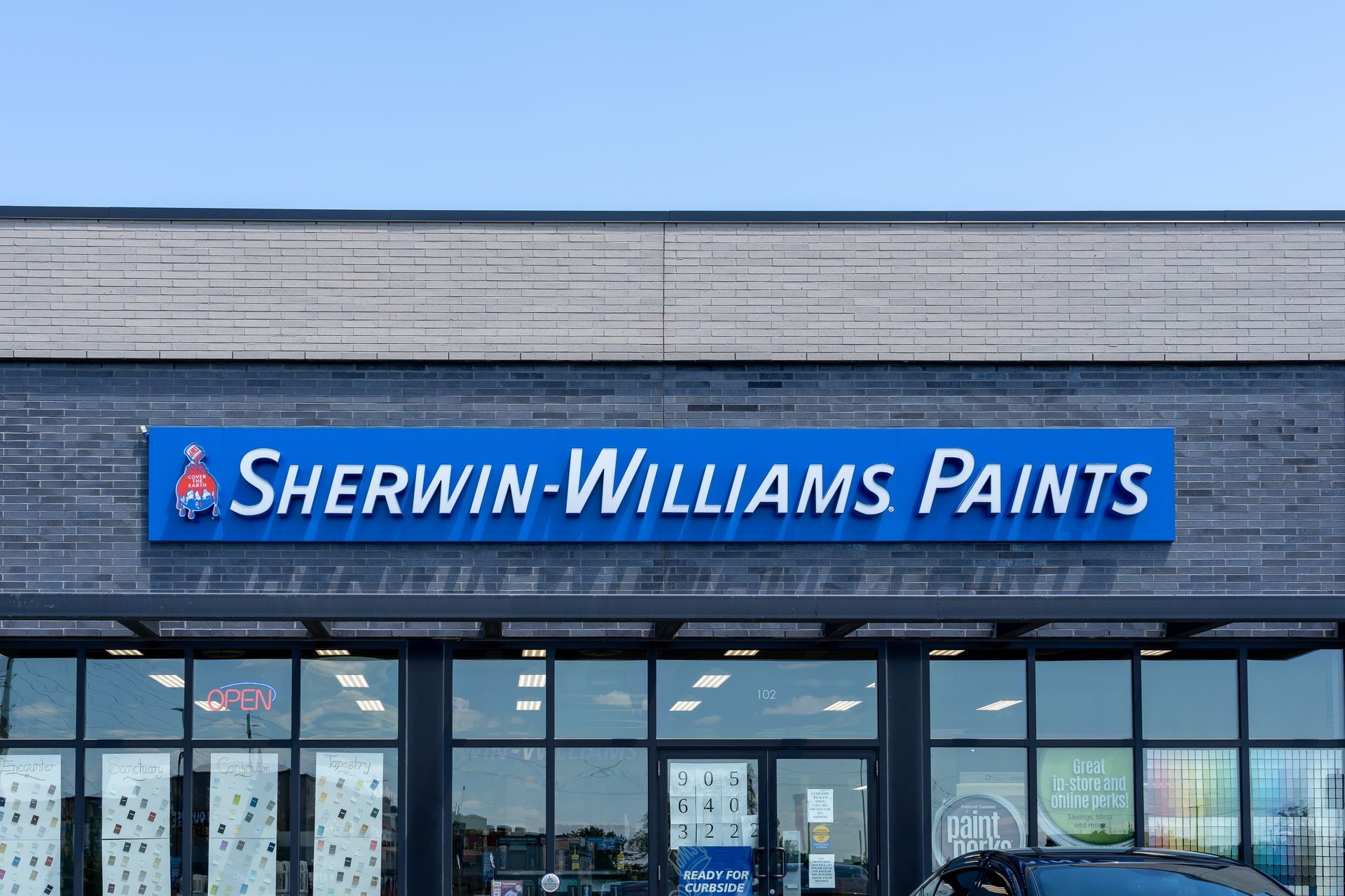 The front of a sherwin williams paints store with a car parked in front of it.