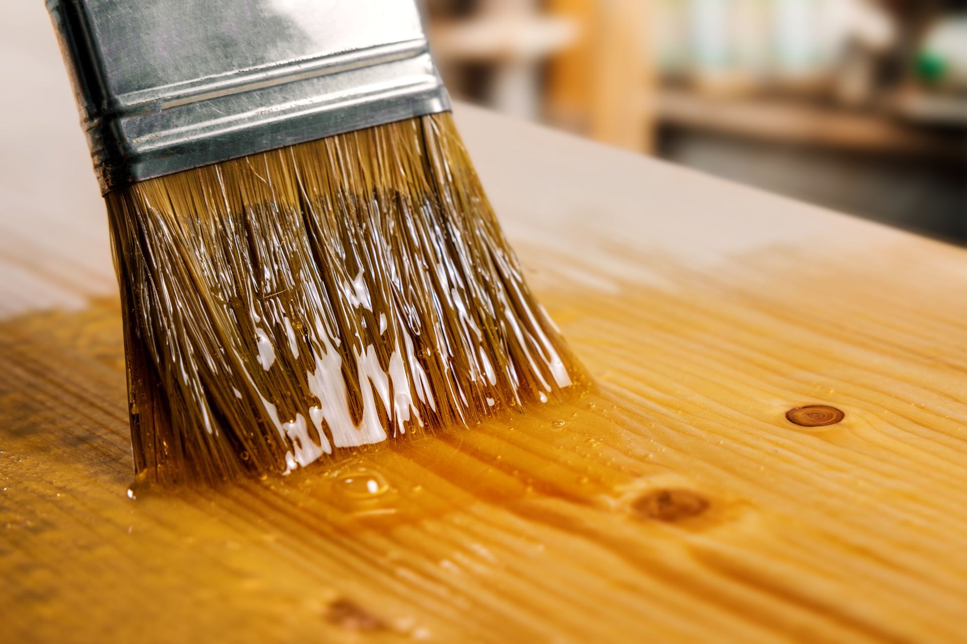 A close up of a brush painting a piece of wood.