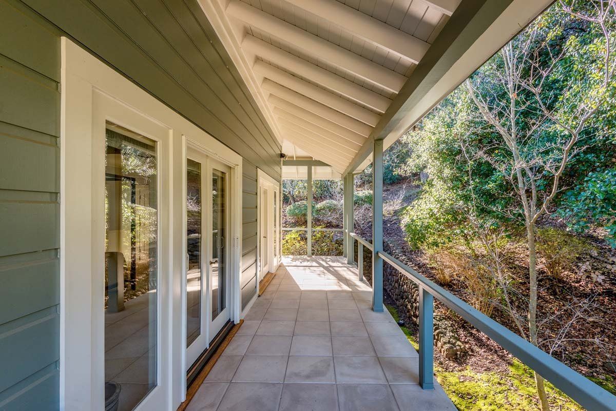 A porch with a roof and trees in the background