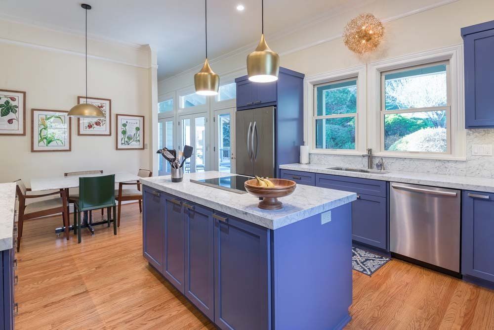 A kitchen with blue cabinets , stainless steel appliances , and a large island.