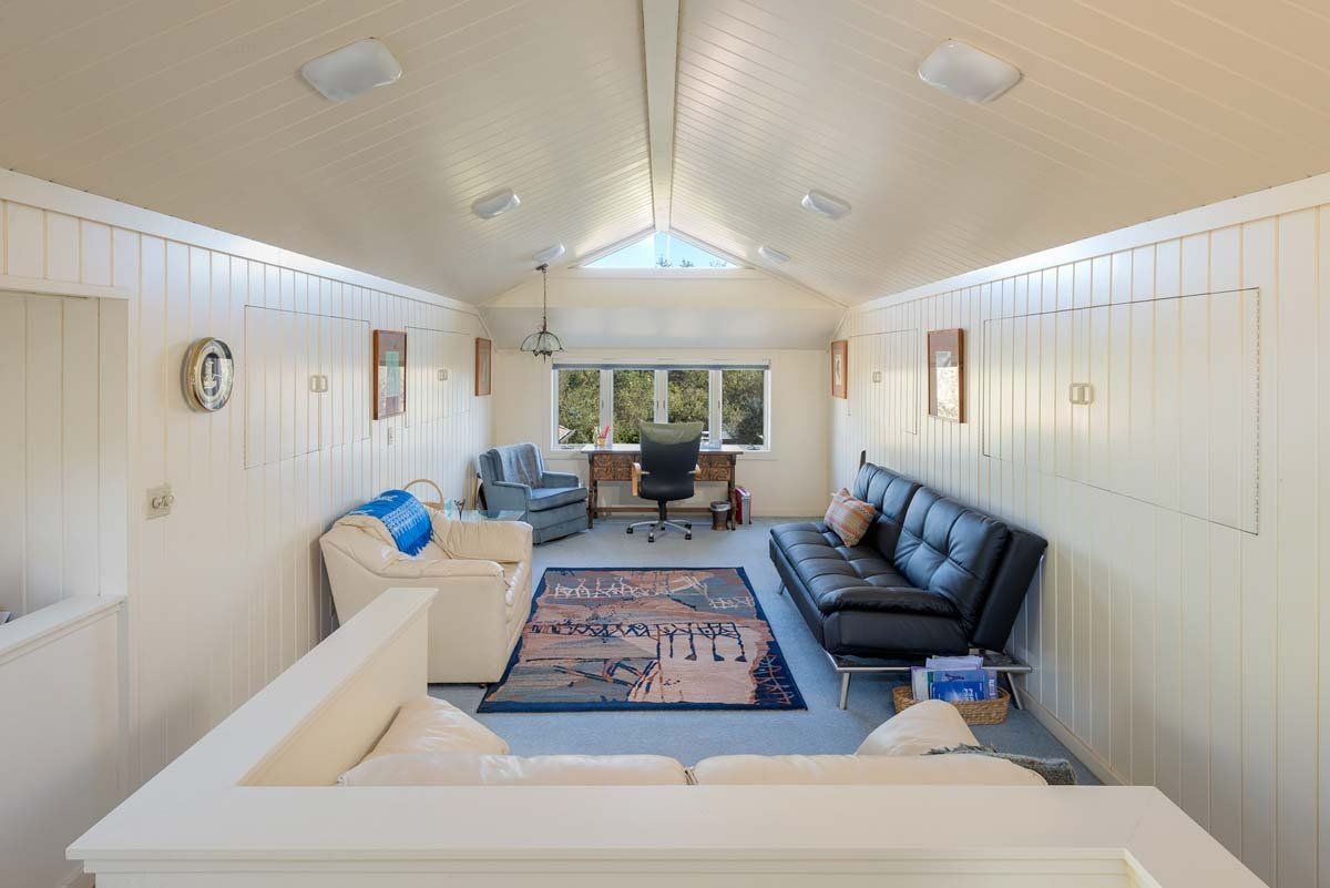 A living room with a couch , chairs , and a desk.
