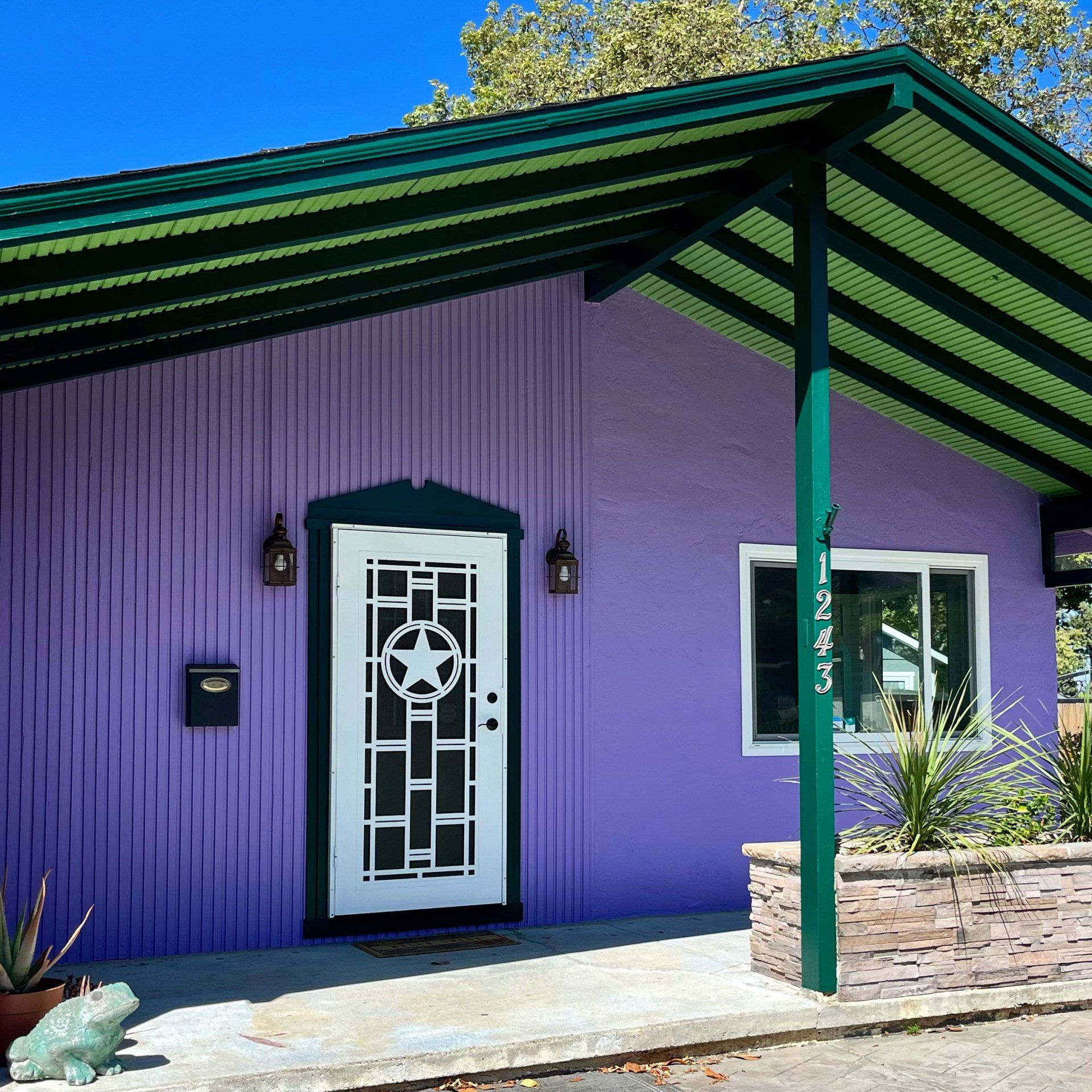 A purple house with a green roof and a white door