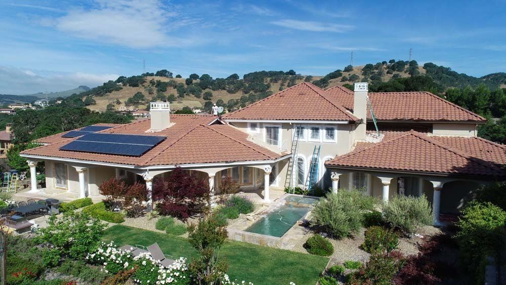 An aerial view of a large house with a pool and solar panels on the roof.