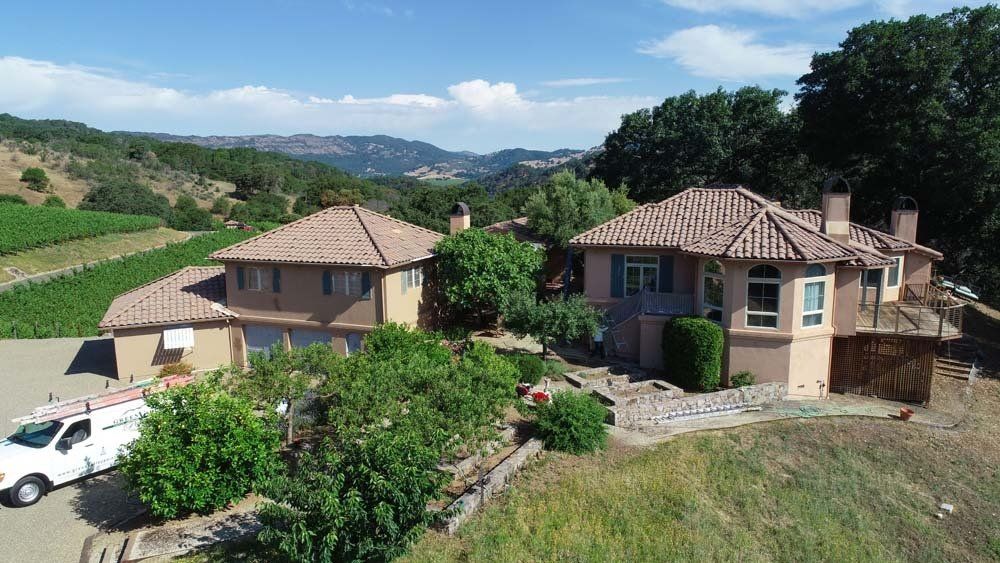 An aerial view of a large house with a white van parked in front of it.