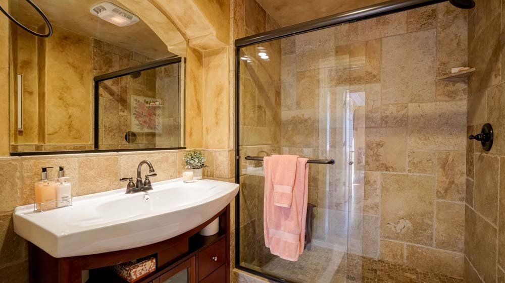 A bathroom with a sink , mirror and walk in shower.