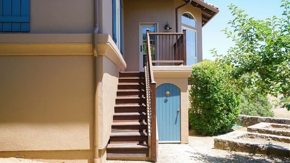 A house with stairs leading up to a blue door