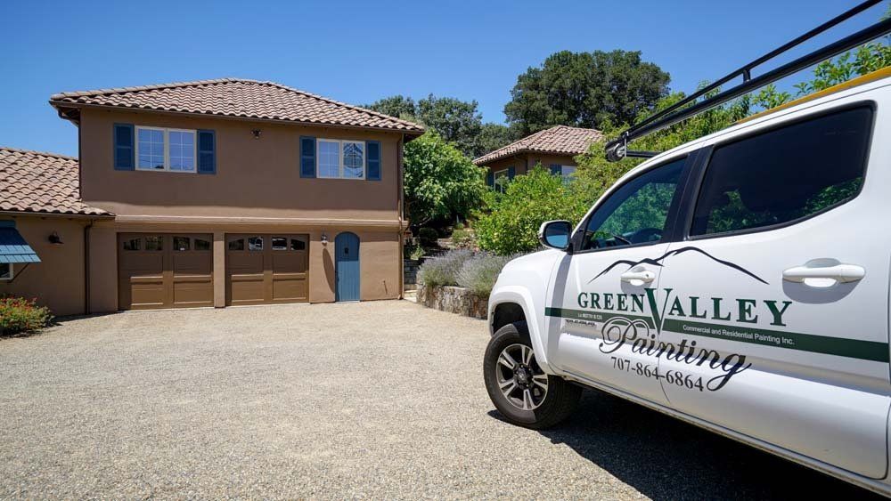 A grey valley painting truck is parked in front of a house