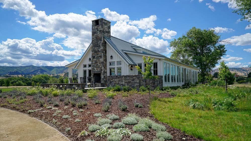 A large white house is sitting in the middle of a grassy field.