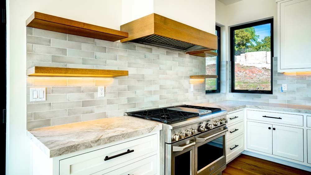 A kitchen with white cabinets , stainless steel appliances , a stove and a window.