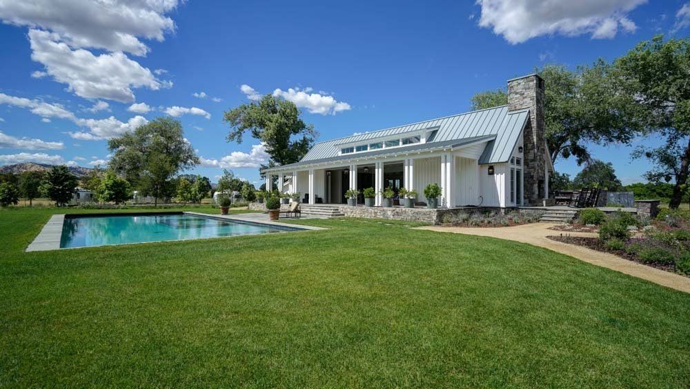 A large white house with a large swimming pool in front of it.