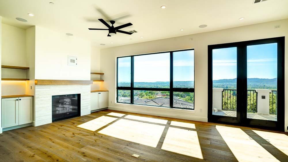 An empty living room with a fireplace , sliding glass doors , and a ceiling fan.
