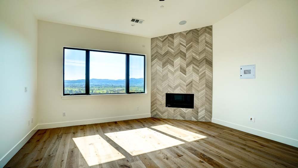 An empty living room with hardwood floors and a fireplace.