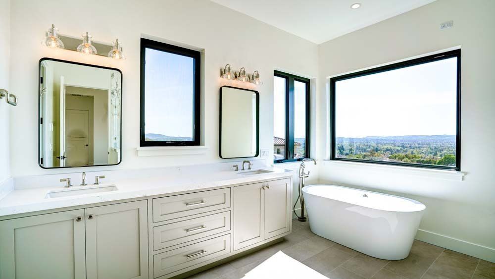 A bathroom with two sinks , a tub , and two mirrors.