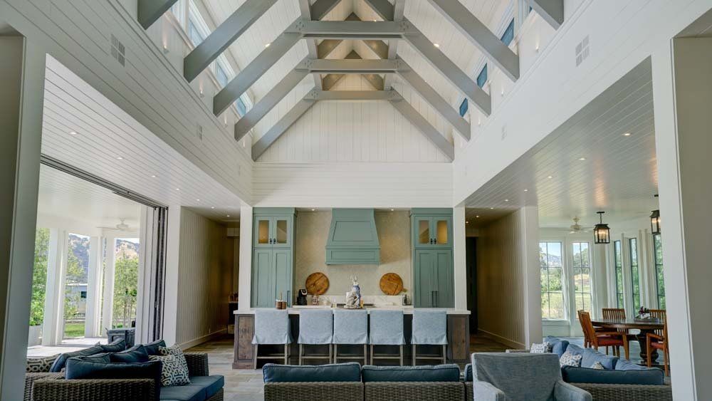 A living room and kitchen in a large house with a vaulted ceiling.