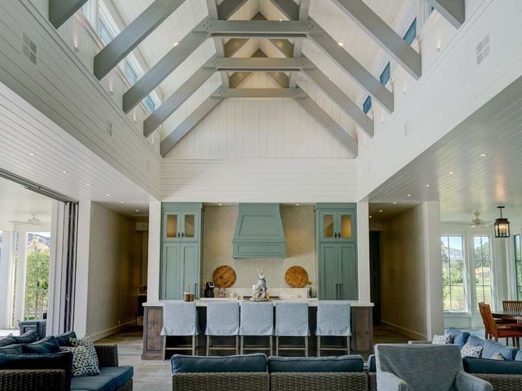 A living room and kitchen in a large house with a vaulted ceiling.