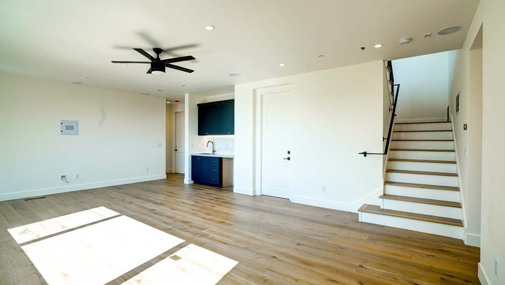 An empty living room with hardwood floors and a ceiling fan