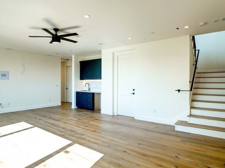 an empty living room with hardwood floors and a ceiling fan .