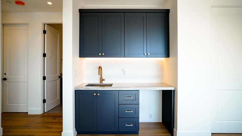 A kitchen with blue cabinets and a sink in a room.