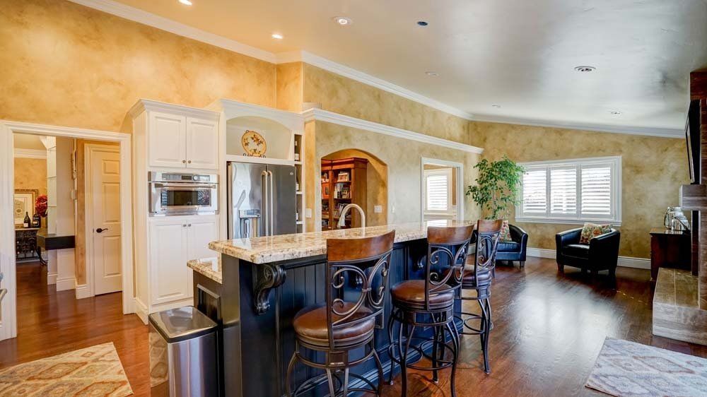 A large kitchen with a bar and stools in a house.