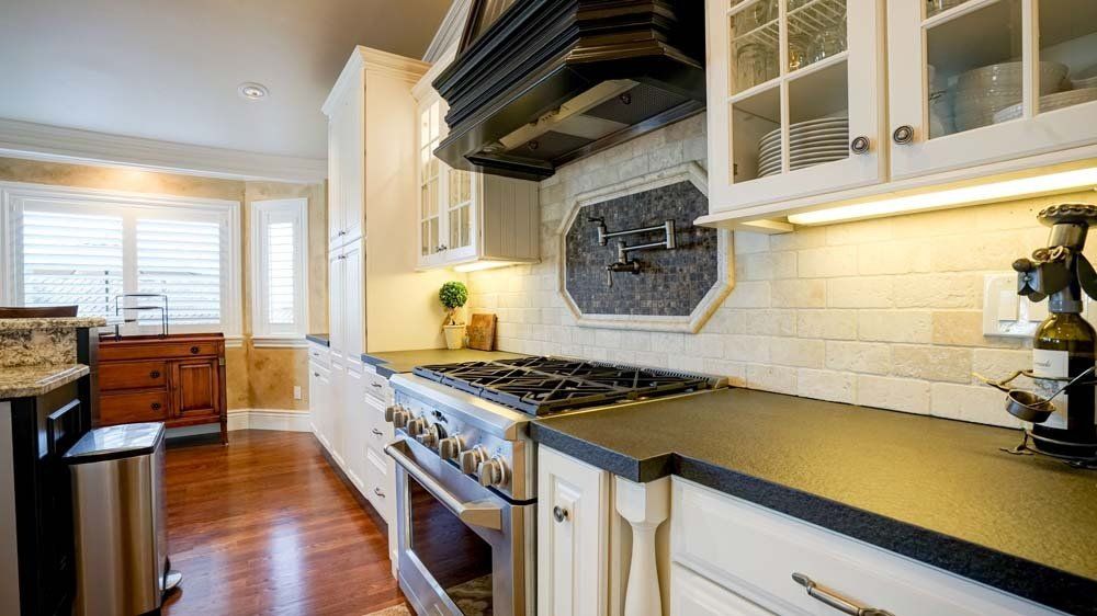 A kitchen with stainless steel appliances and black counter tops.