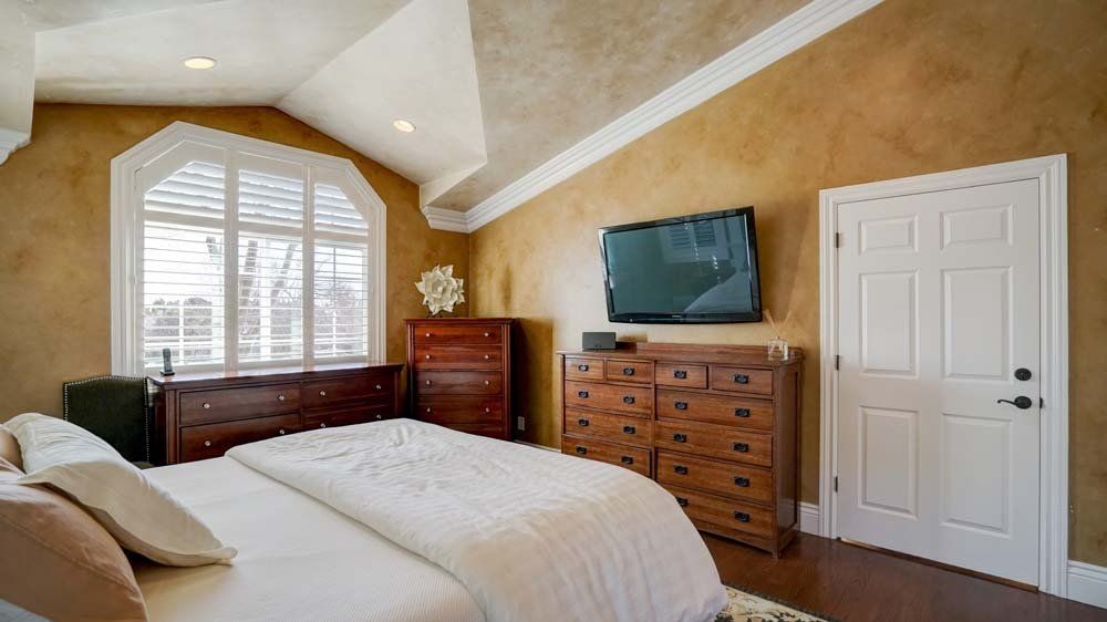 A bedroom with a bed , dresser , and television on the wall.