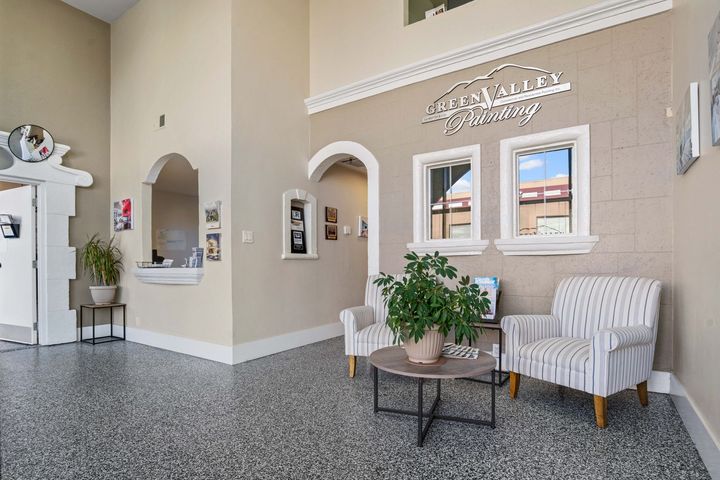 There are two chairs and a table in the lobby of Green Valley Painting.