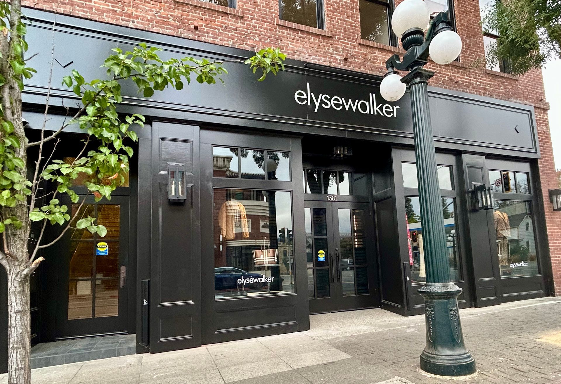 A black building with a brick building in the background and a street light in front of it.