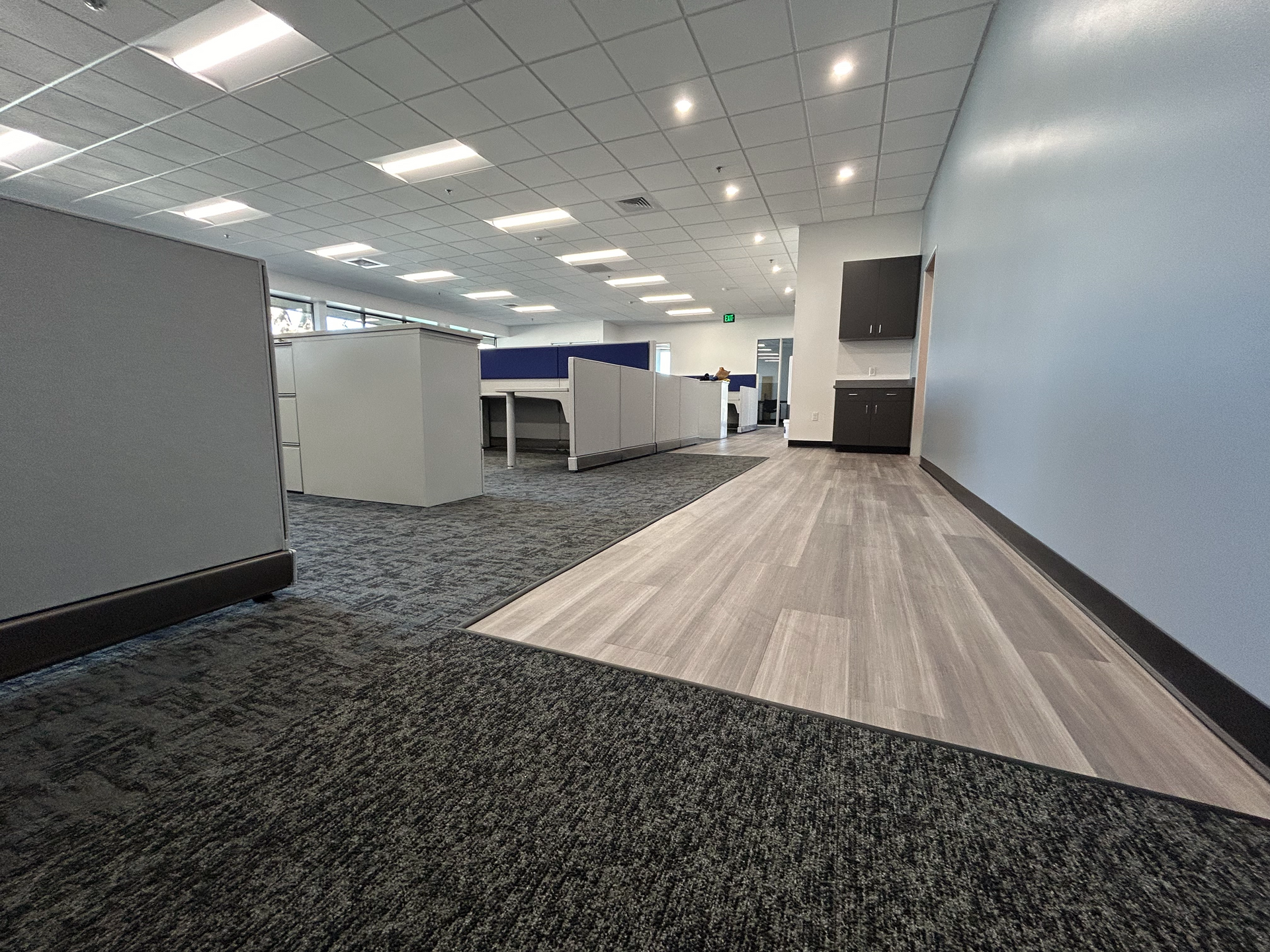 A large empty office with a carpeted floor and cubicles.