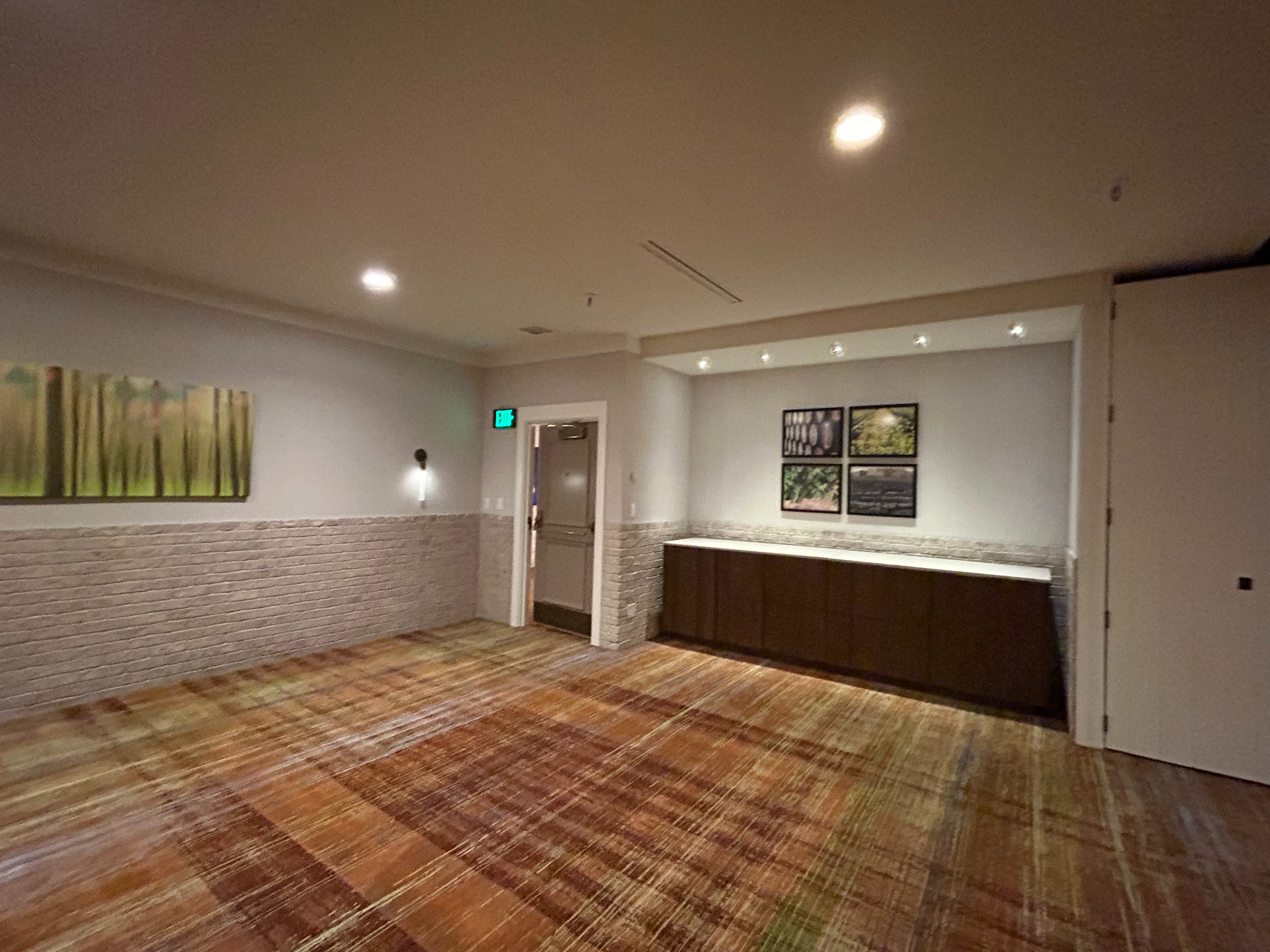 An empty room with a wooden floor and a painting on the wall.