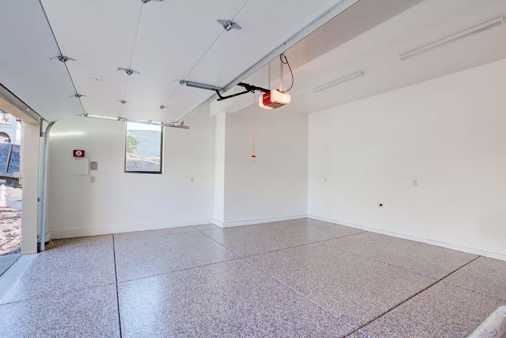An empty garage with a garage door open and a projector screen on the wall.