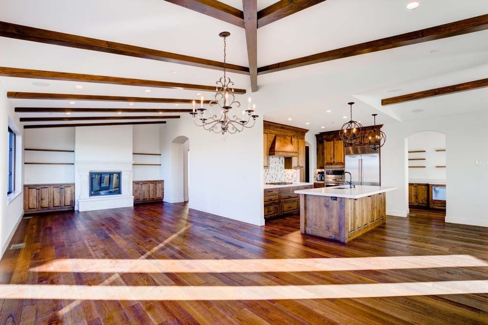 A large empty room with hardwood floors and a chandelier hanging from the ceiling.