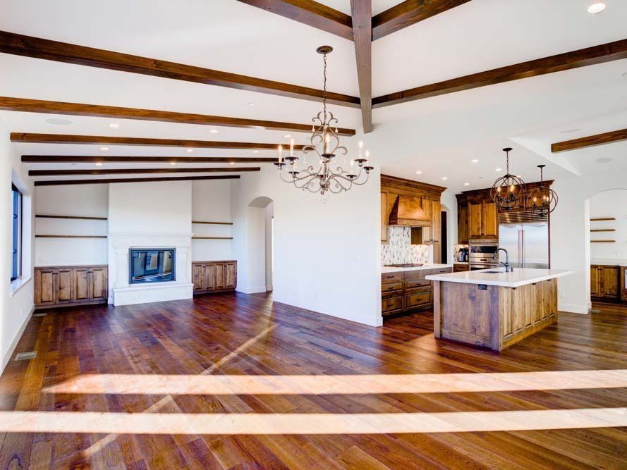 A large empty room with hardwood floors and a chandelier hanging from the ceiling.