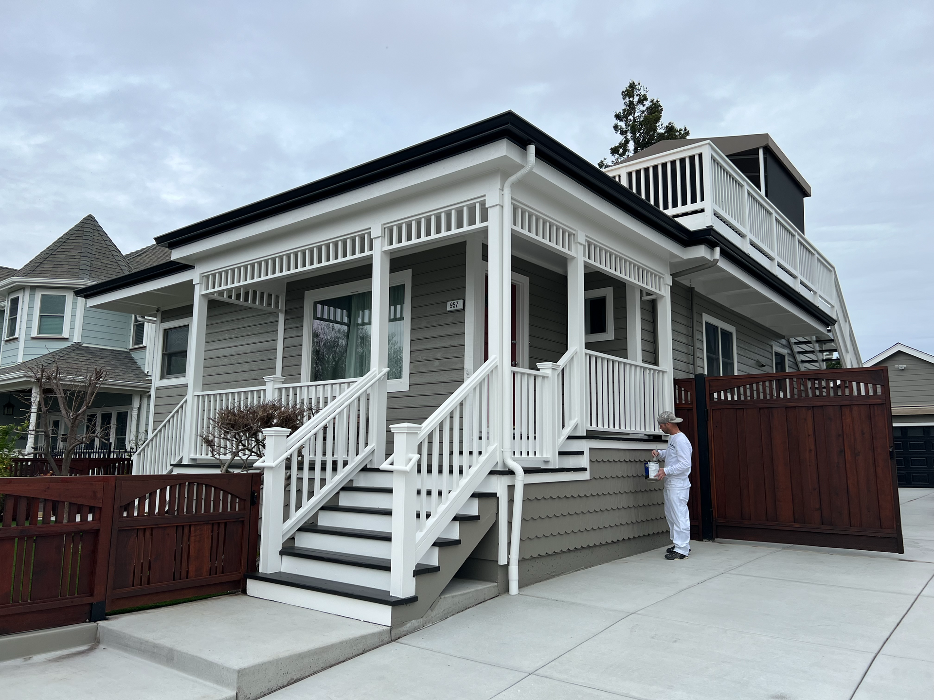 A man is standing in front of a house with stairs and a porch.