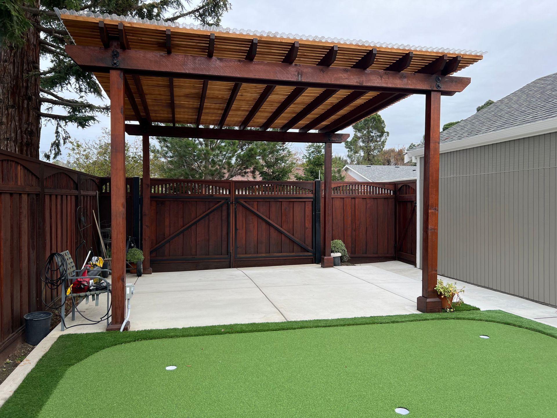A backyard with a pergola and a putting green.