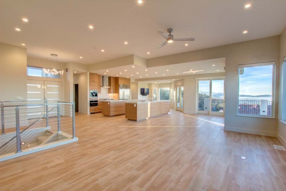 A large empty room with hardwood floors and a ceiling fan.