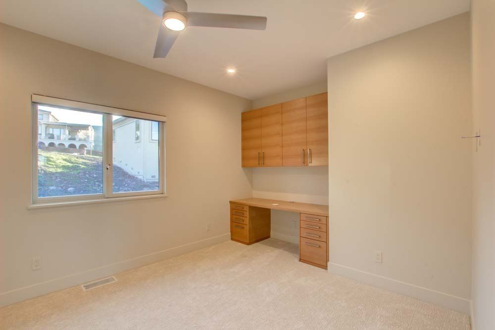 An empty room with a desk and a ceiling fan.