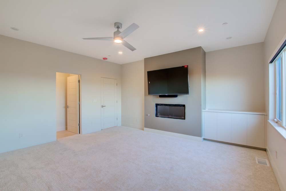 An empty room with a fireplace and a flat screen tv on the wall.