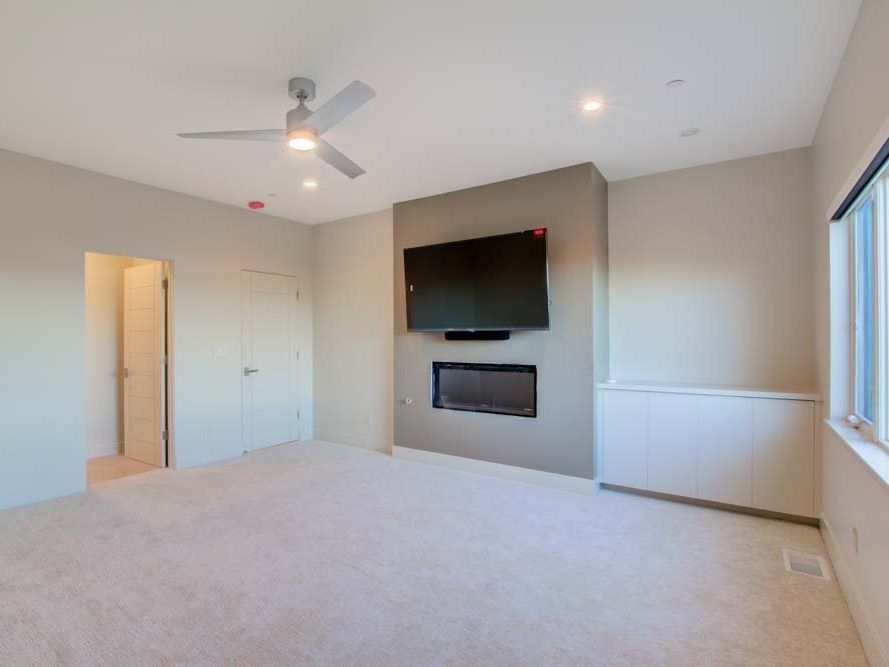 An empty room with a fireplace and a flat screen tv on the wall.