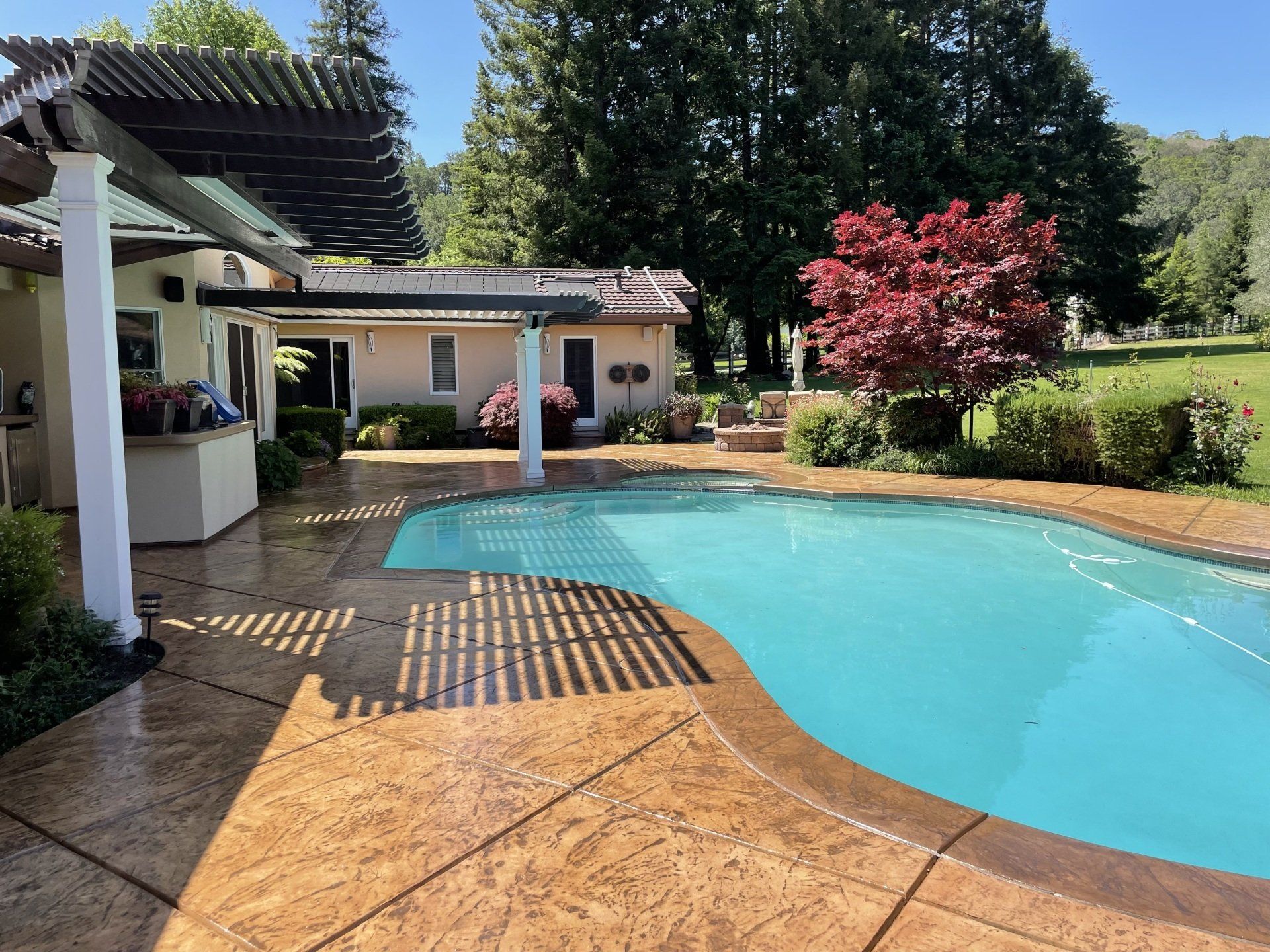 A large swimming pool is in the backyard of a house