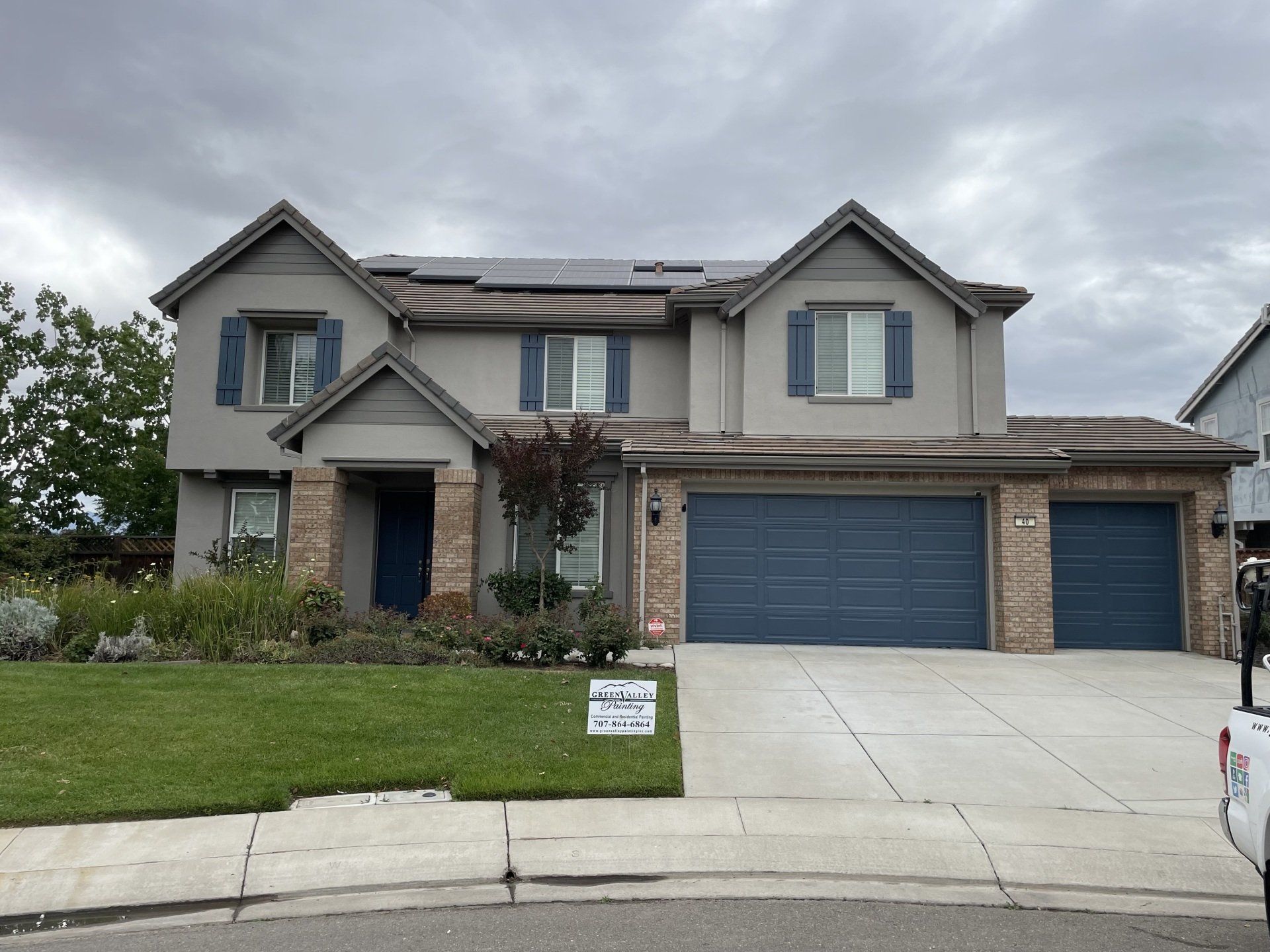 A large house with blue garage doors and a sign in front of it