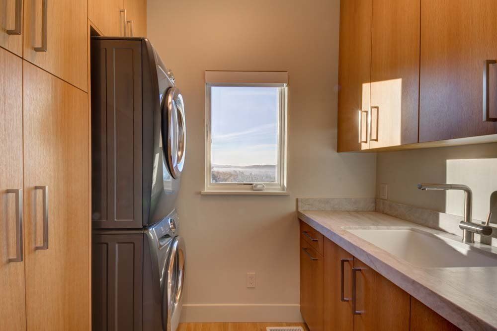 A laundry room with a washer and dryer stacked on top of each other and a sink.