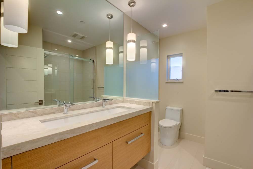A bathroom with two sinks , a toilet , and a large mirror.