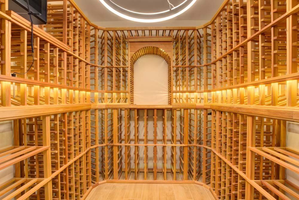 A large wooden wine cellar with lots of shelves filled with wine bottles.