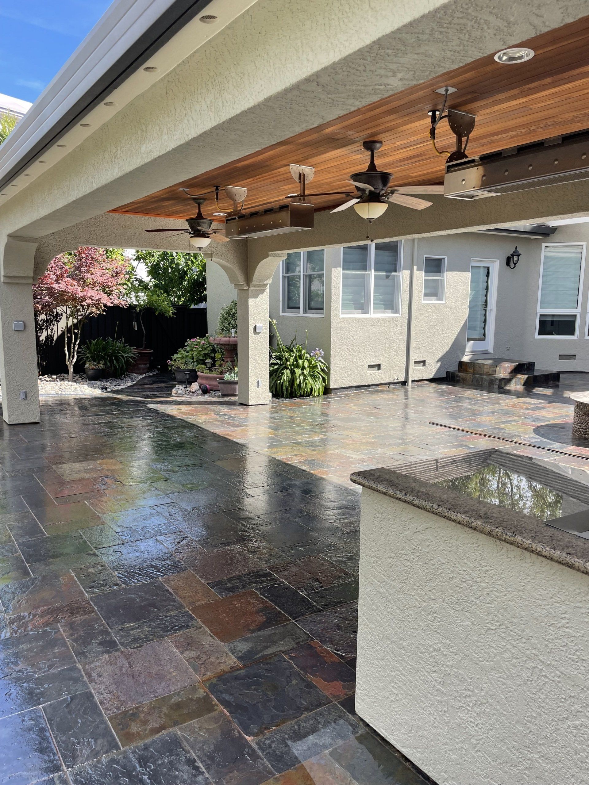 A patio with a ceiling fan and a sink in front of a house.