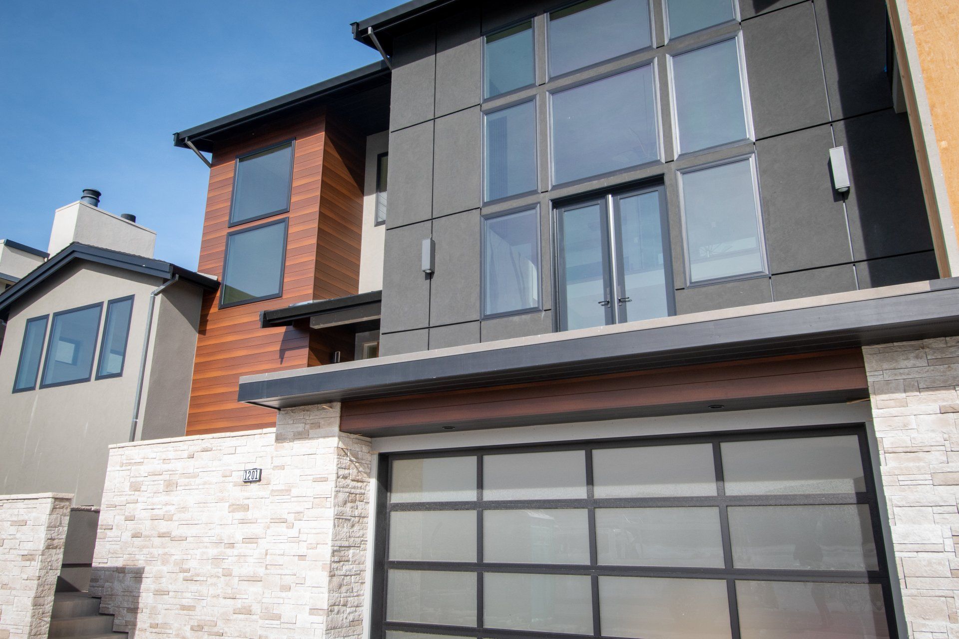 A modern house with a large garage door and lots of windows.