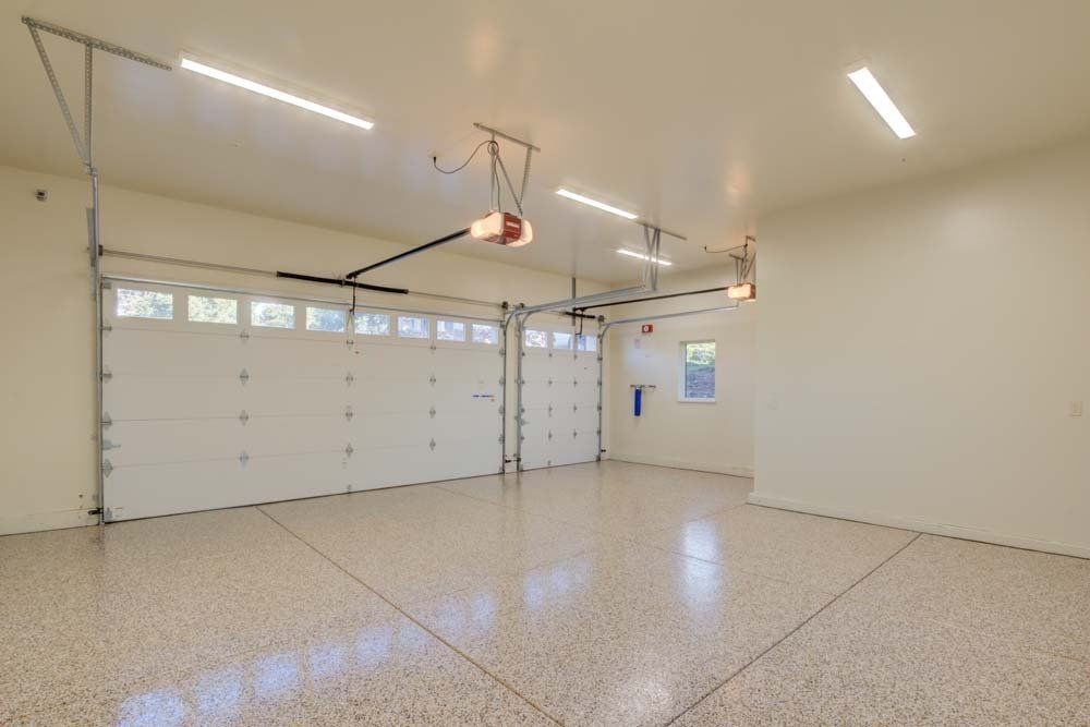 An empty garage with a garage door open and a ceiling fan.