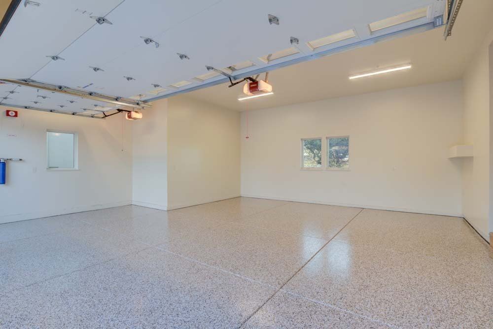 An empty garage with a garage door open and a window.